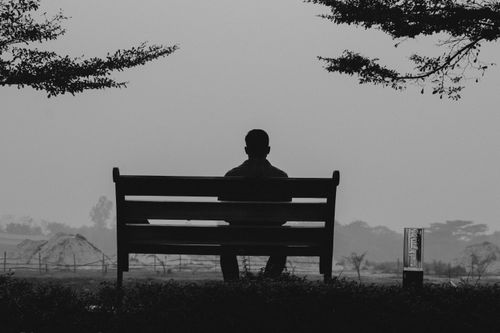 Free A black and white silhouette of a man sitting on a bench outdoors in Dhaka, Bangladesh. Stock Photo