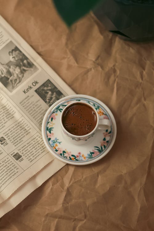 A Cup of Coffee Standing next to a Newspaper