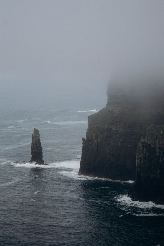 Sea stack below misty coastal cliffs — photo by Liudmyla Shalimova on Pexels