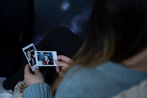 2枚の写真を保持している女性