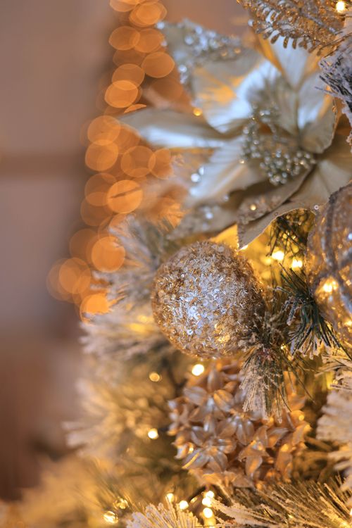 Free Beautiful close-up of a Christmas tree decorated with sparkling gold ornaments and lights. Stock Photo