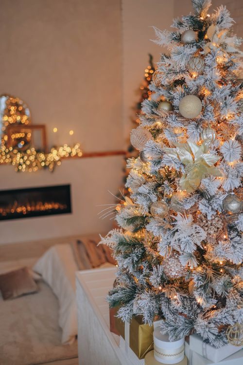 Free Warm living room featuring a beautifully decorated Christmas tree with golden lights and ornaments. Stock Photo