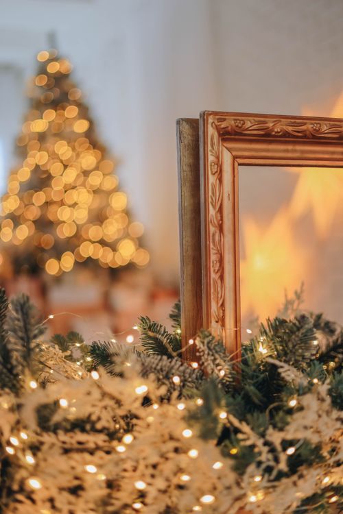 Free Blurred Christmas tree lights with decorative frame in foreground create a cozy festive atmosphere. Stock Photo
