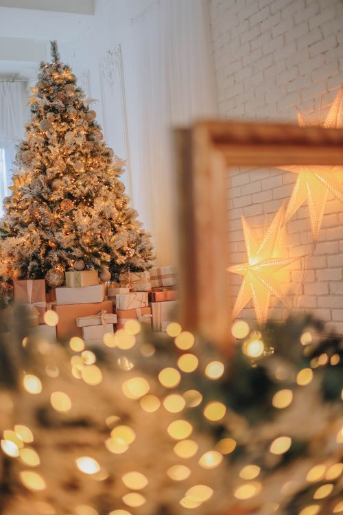 Free Cozy indoor scene of a decorated Christmas tree with glowing lights and star ornaments. Stock Photo