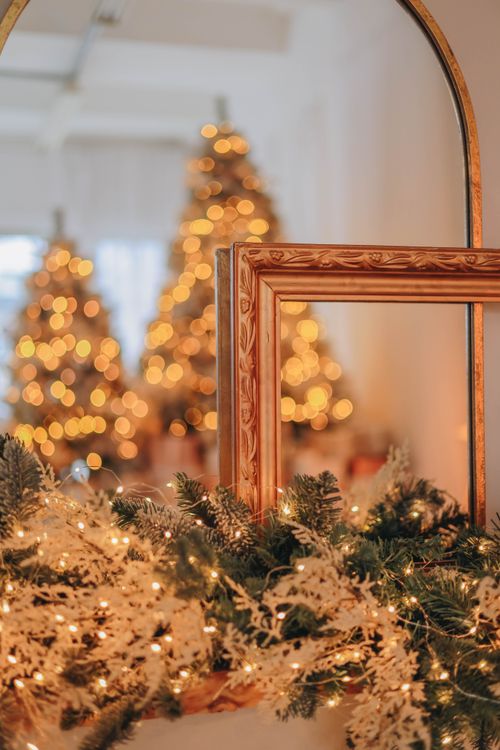 Free Festive scene with Christmas trees and lights reflecting in a mirror, creating a warm holiday ambiance. Stock Photo