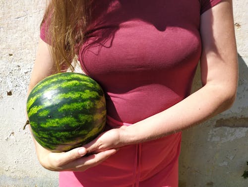 A Woman in a Pink Shirt Holding a Watermelon