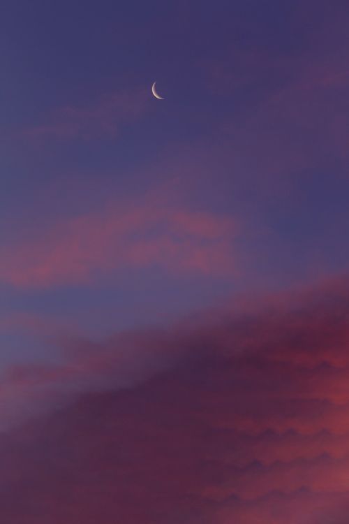 Free Crescent moon with colorful pink and purple clouds in a dramatic evening sky. Stock Photo