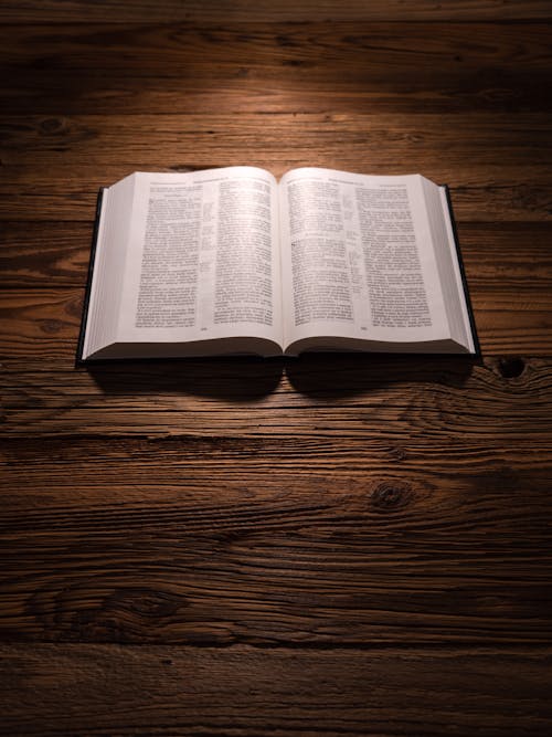 An Opened Bible Lying on a Wooden Background 