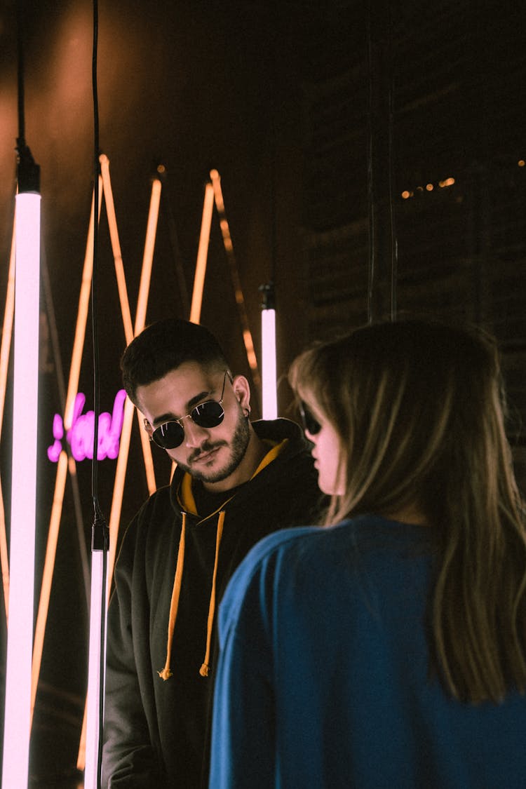 Young Man And Woman In Sunglasses Standing In A Room With Modern Lights 