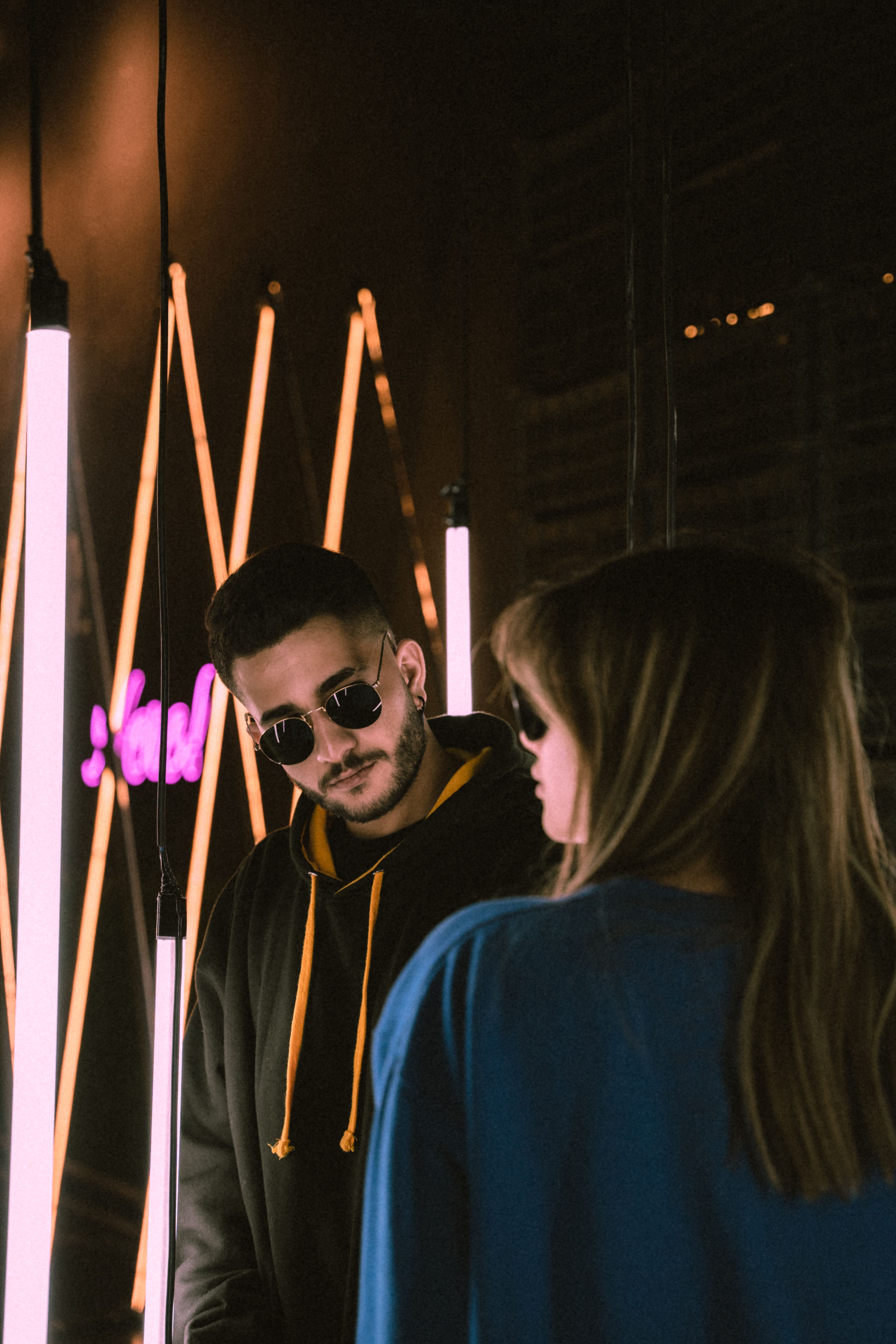 Young Man and Woman in Sunglasses Standing in a Room with Modern Lights ...