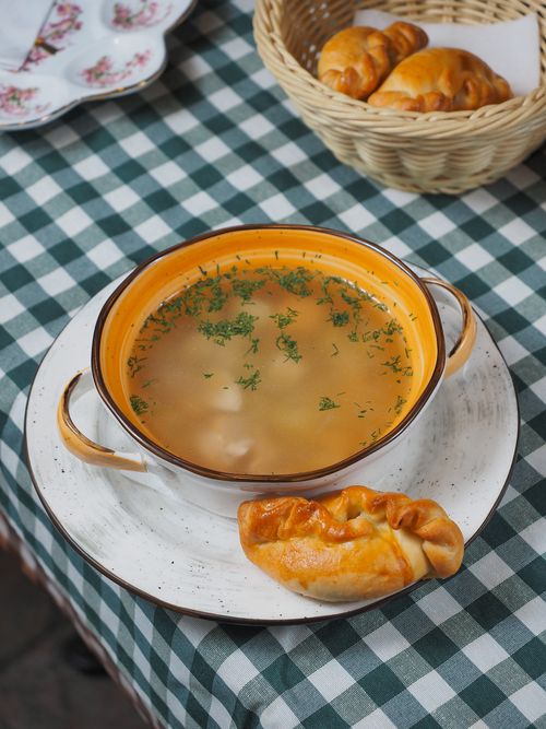 Free Bowl of savory soup with pastries on a checkered tablecloth, ideal for food photography. Stock Photo