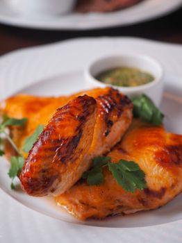 Close-up of juicy grilled chicken garnished with fresh parsley on a plate.