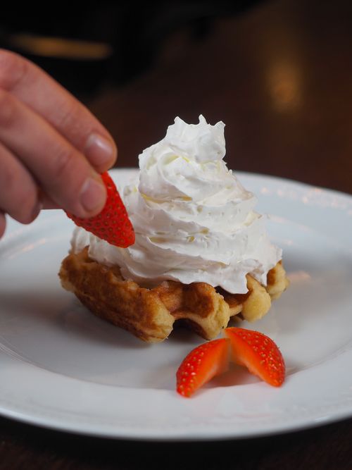 Free Appetizing waffle with whipped cream and fresh strawberries on a plate, perfect for dessert lovers. Stock Photo