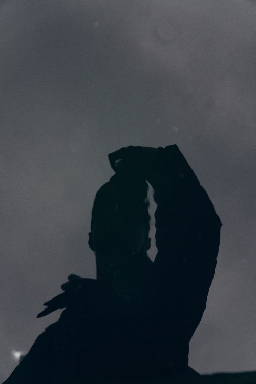 Free Artistic silhouette of a person reflected against a cloudy, overcast sky. Stock Photo