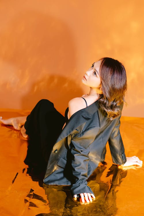 Woman Sitting and Posing on Orange Background