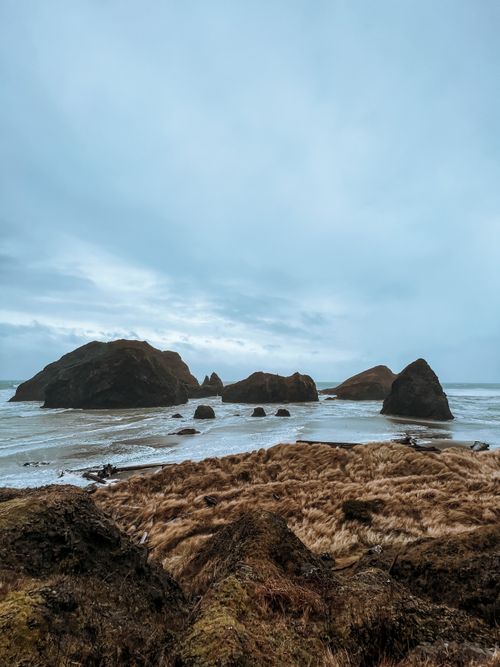 Free Majestic rocky coastline at sunset with waves crashing on the shore and dramatic sky. Stock Photo