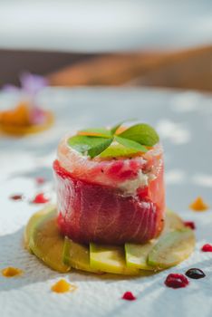 Close-up of gourmet sushi garnished with avocado and edible flowers.