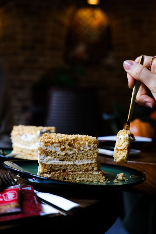 Free Delicious tiramisu cake slice with a hand holding a fork in an Istanbul café setting. Stock Photo