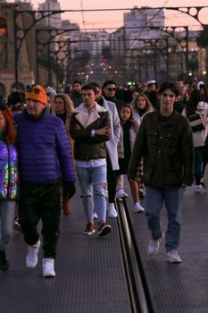 People walking on a busy street in Porto at dusk, capturing urban life and city atmosphere.