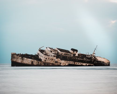 Free A decaying shipwreck resting on the calm sea, showcasing a blend of rust and elegance. Stock Photo