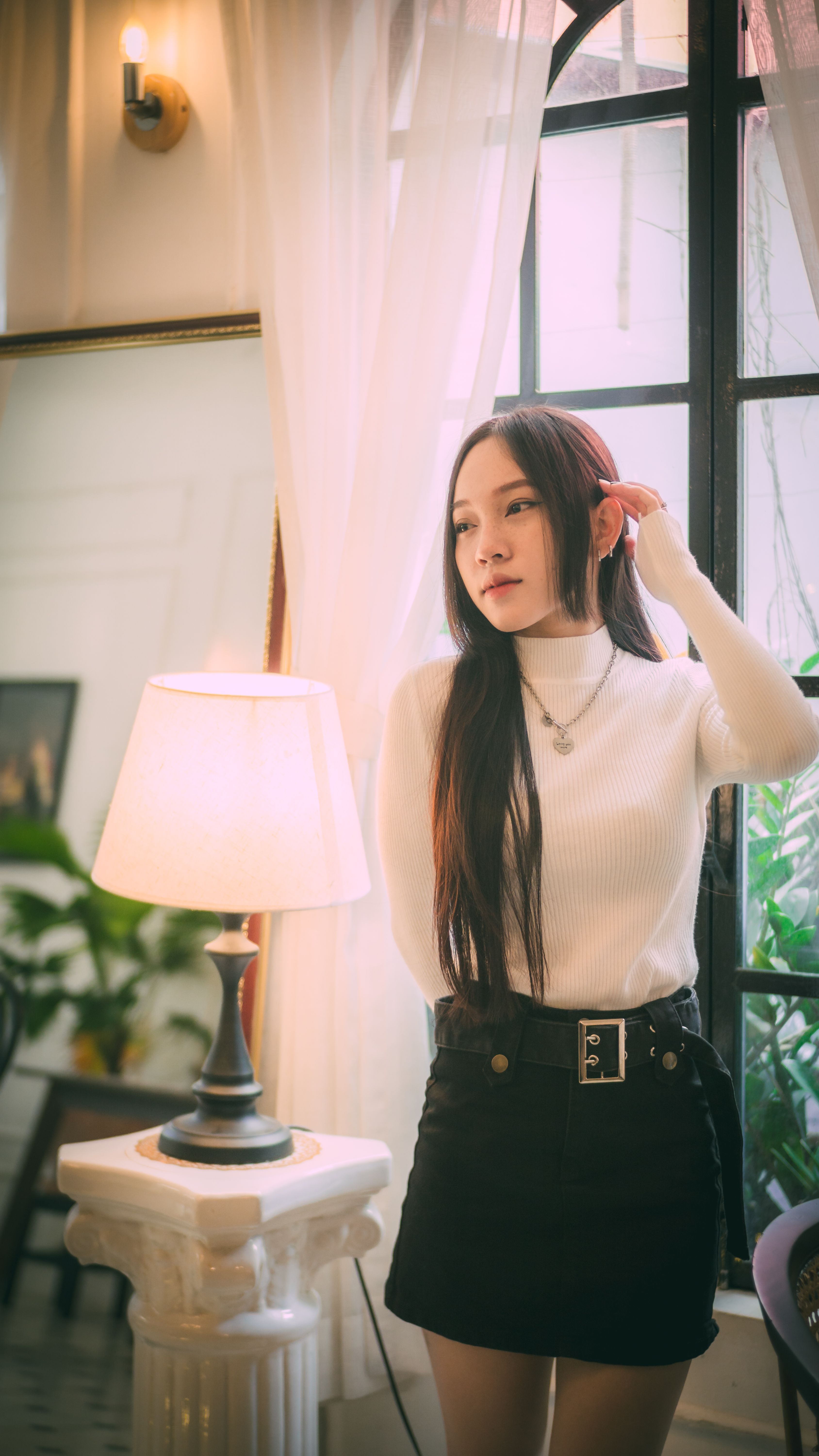 Portrait of a woman standing indoors with soft natural light and modern decor.