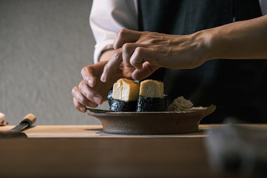 Close-up of a chef's hands crafting sushi with precision in a cozy indoor setting.