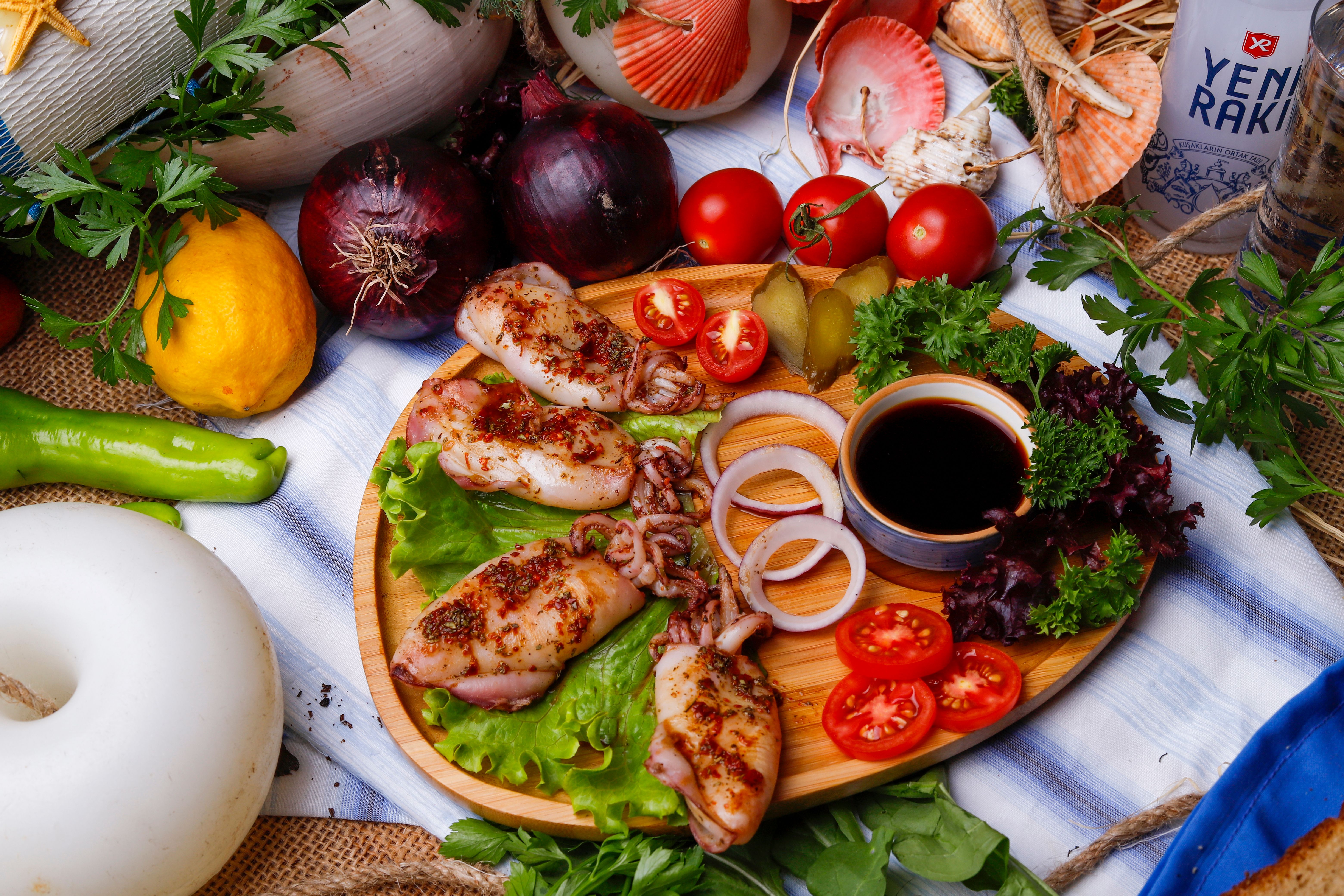 Grilled calamari steaks on a wooden board with herbs
