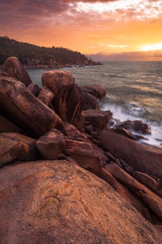 Explore the rocky shoreline of Arthur Bay, Australia, during a stunning sunset with vivid skies.