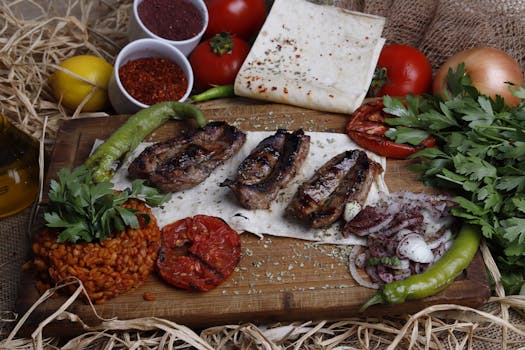 Delicious grilled meat served with fresh vegetables, herbs, and spices on a rustic cutting board.