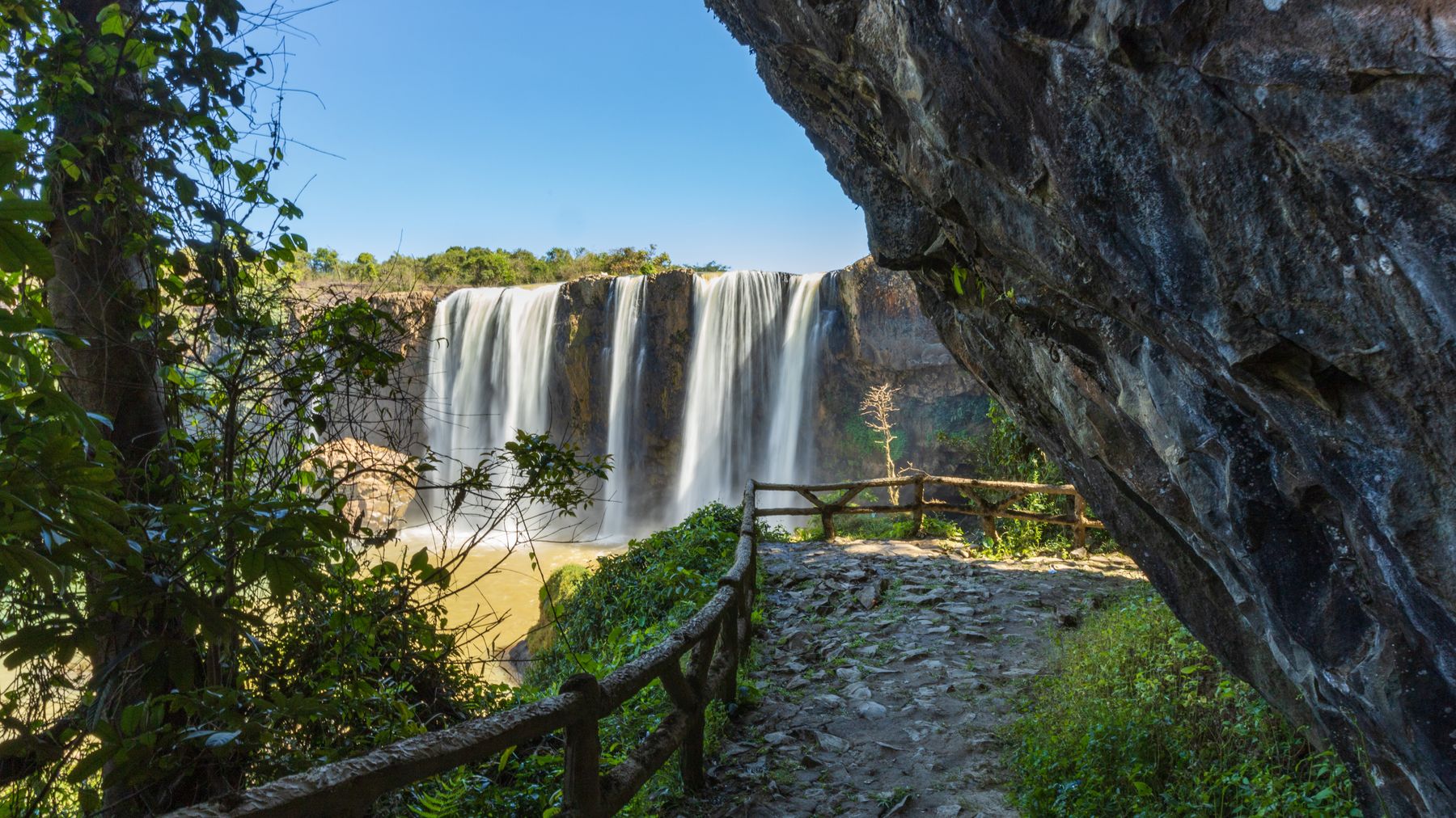 Explore the breathtaking waterfall with lush greenery and rocky cliffs in Vietnam's Lâm Đồng Province.