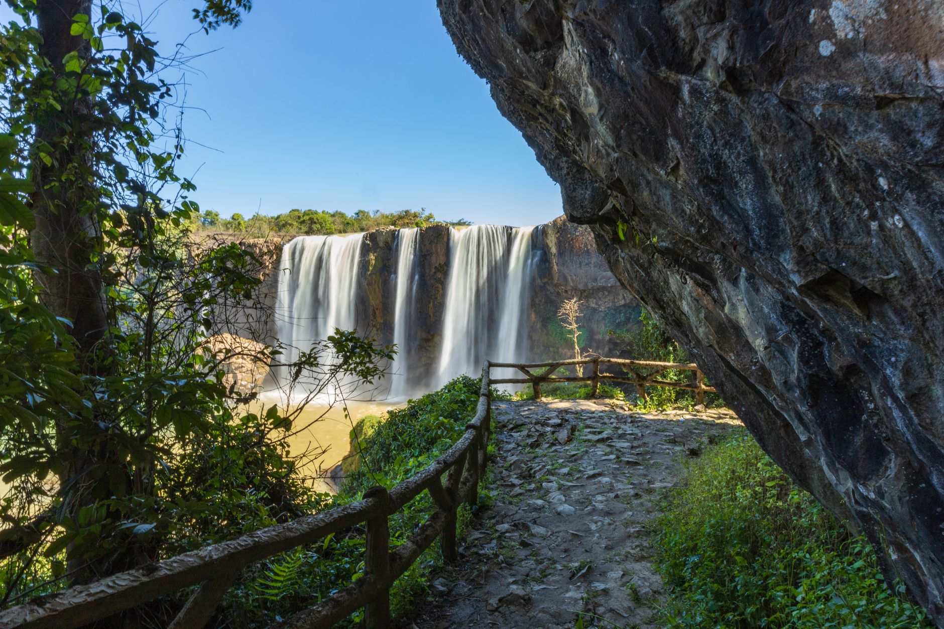 Explore the breathtaking waterfall with lush greenery and rocky cliffs in Vietnam's Lâm Đồng Province.
