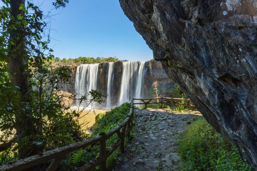 Explore the breathtaking waterfall with lush greenery and rocky cliffs in Vietnam's Lâm Đồng Province.