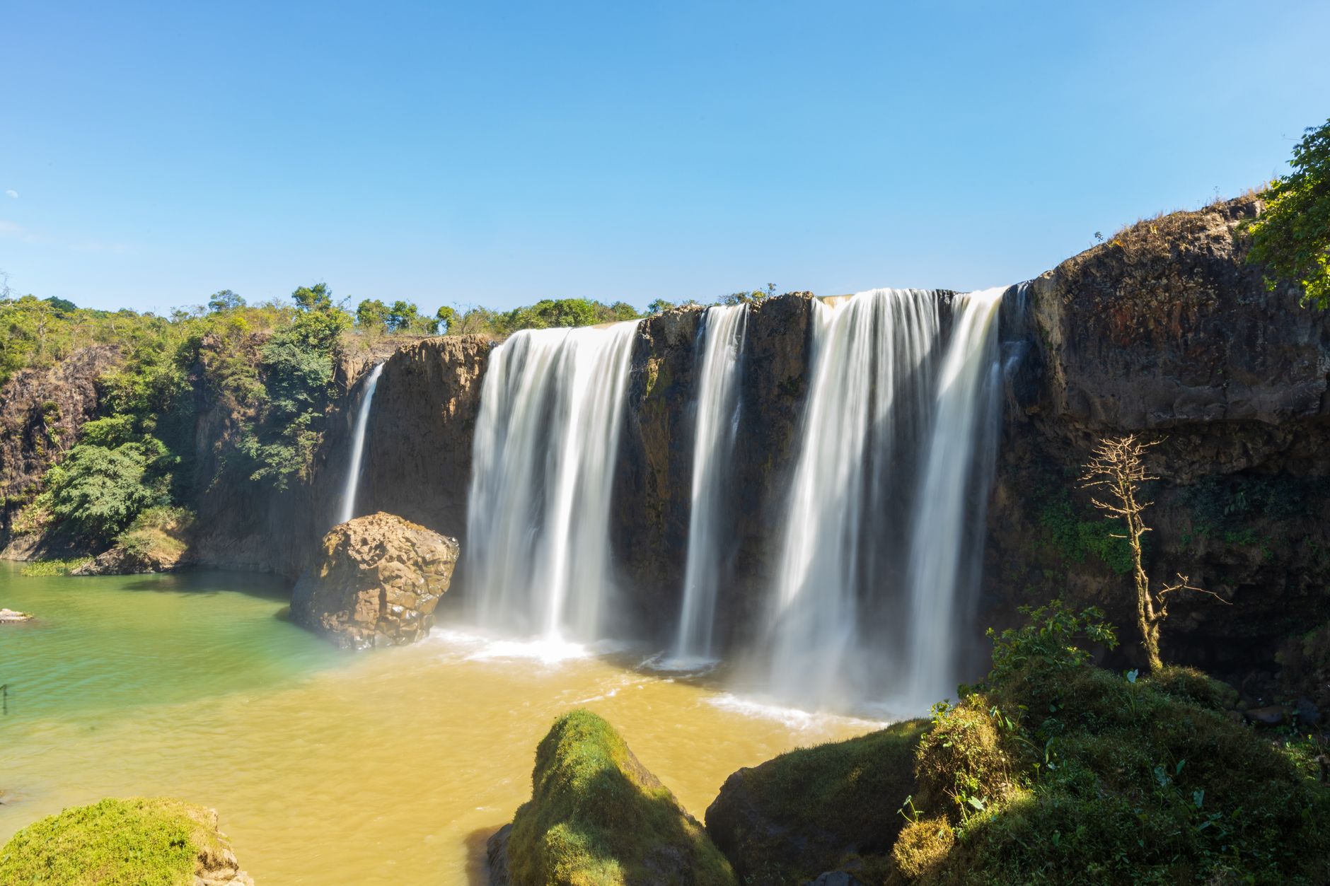 Stunning waterfall under a clear blue sky in Lâm Đồng, Vietnam, showcasing natural beauty.