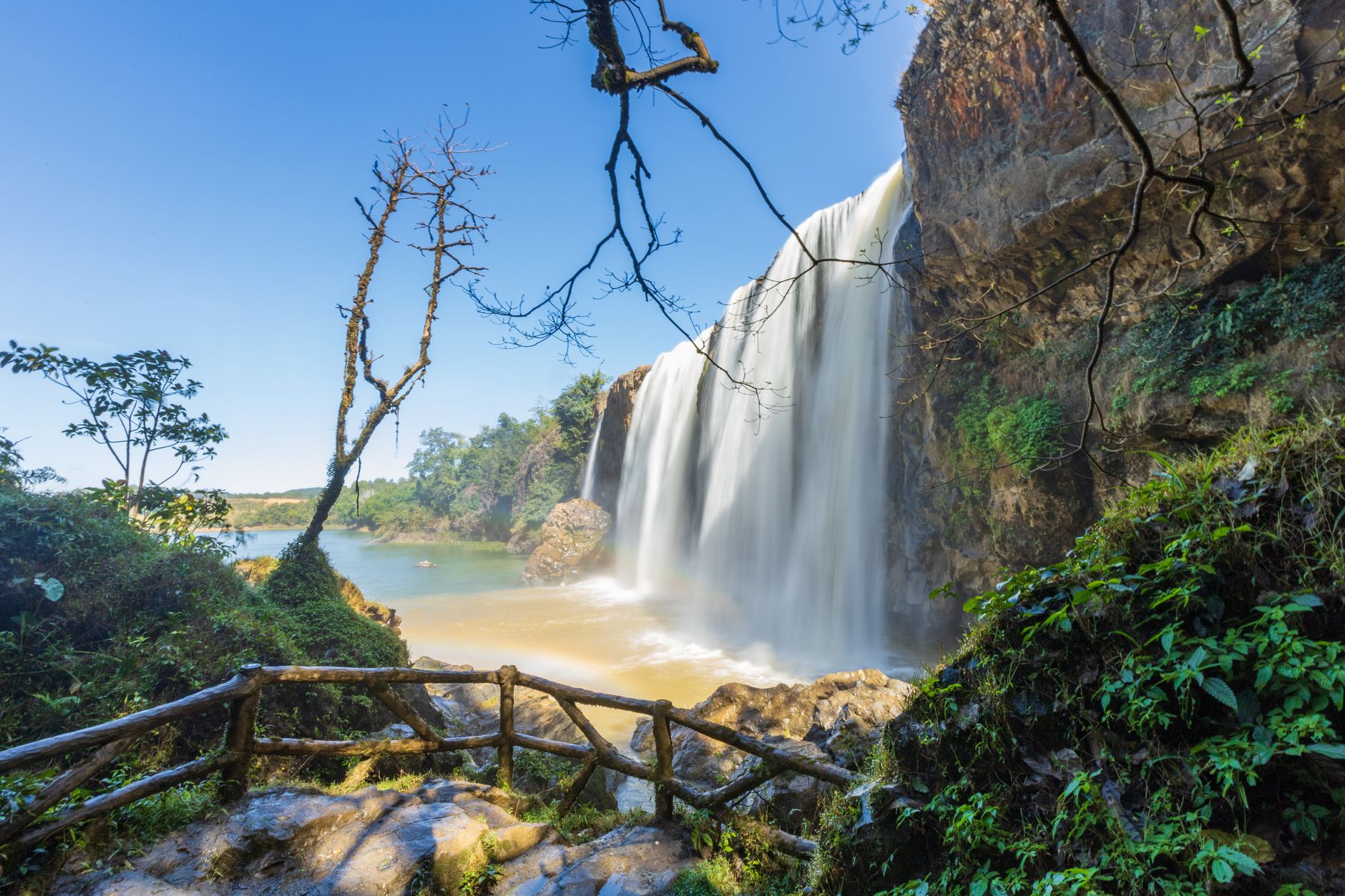 Stunning waterfall cascading down rocks in Vietnam's lush natural park, surrounded by lush greenery.