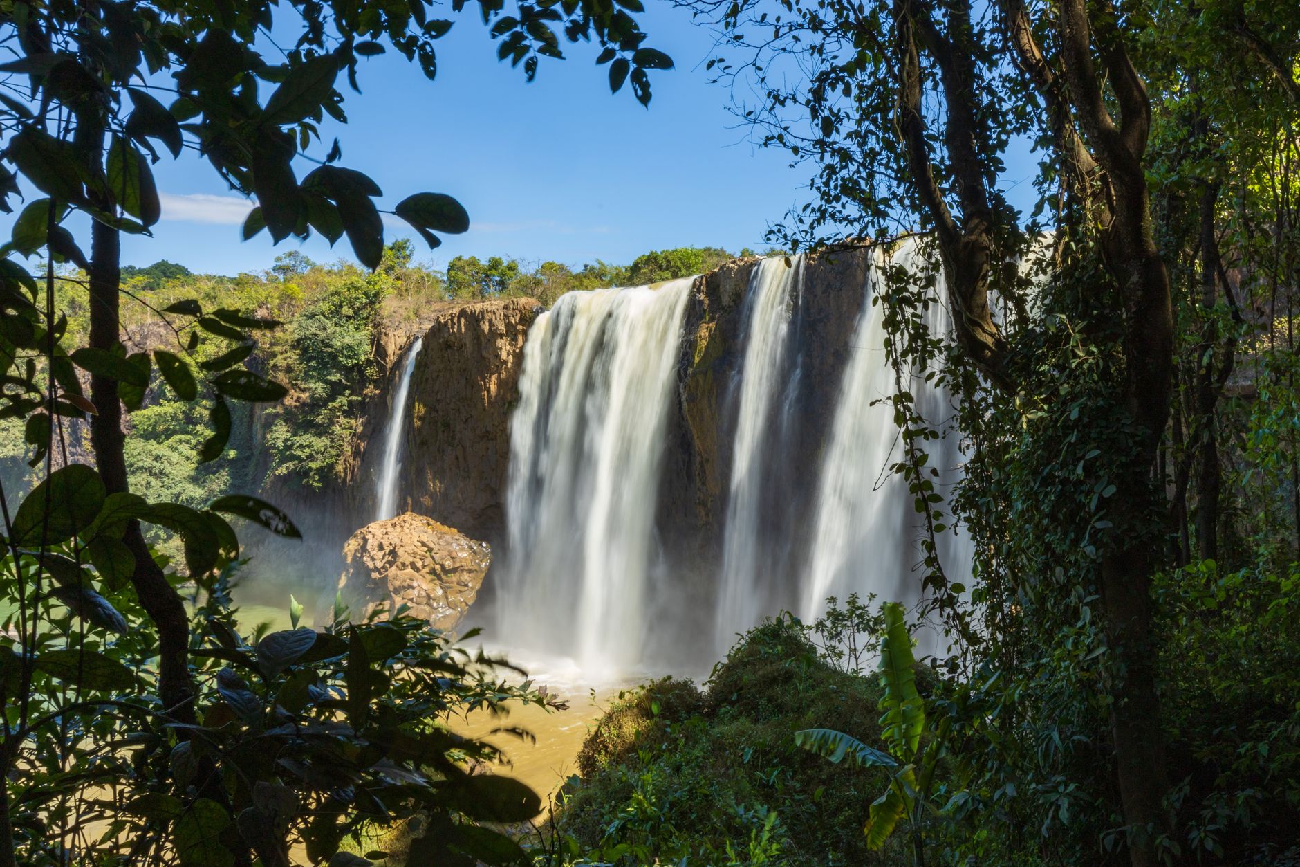 Stunning view of a waterfall cascading down rocks surrounded by lush greenery in Vietnam.