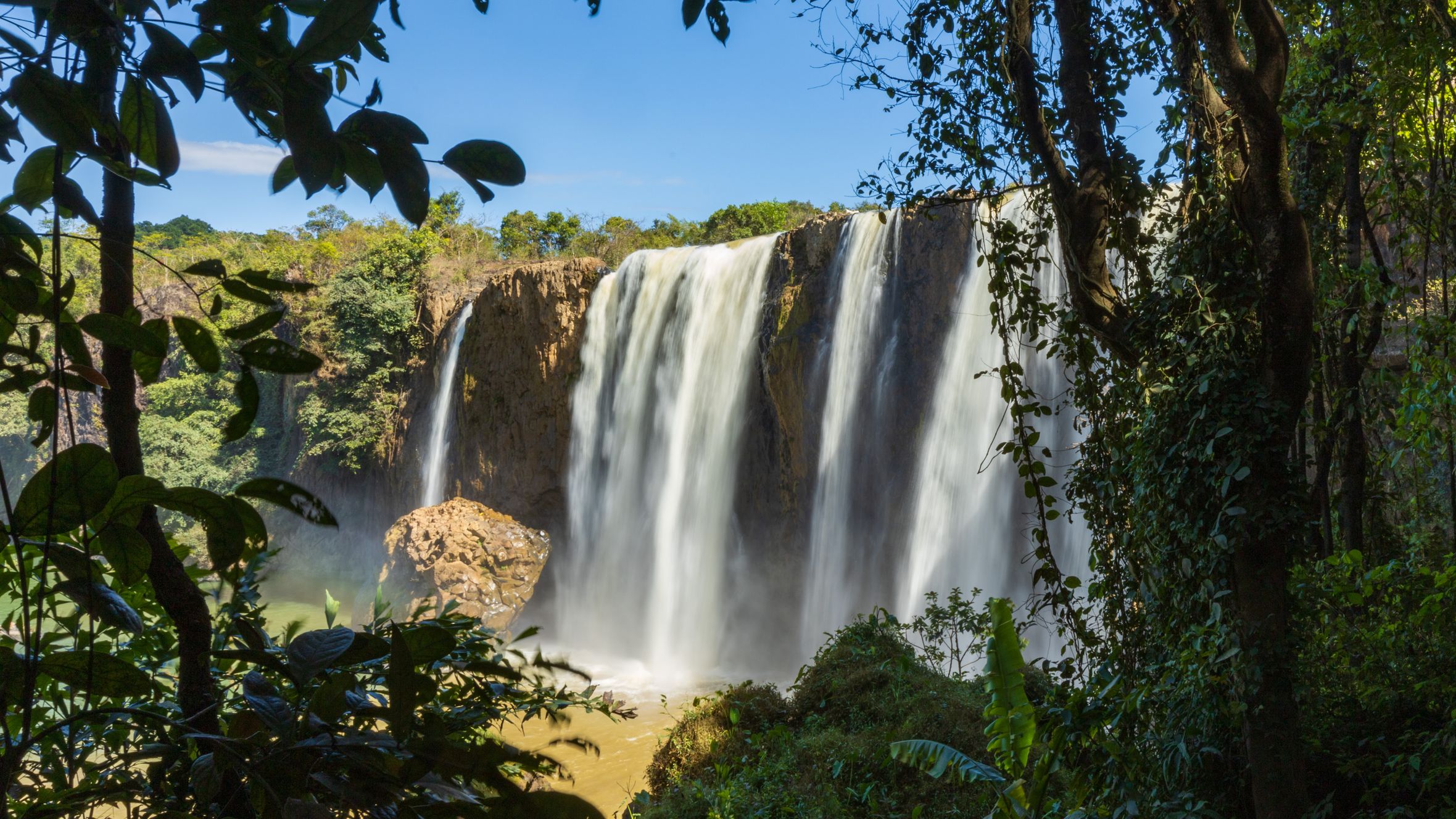 Stunning view of a waterfall cascading down rocks surrounded by lush greenery in Vietnam.