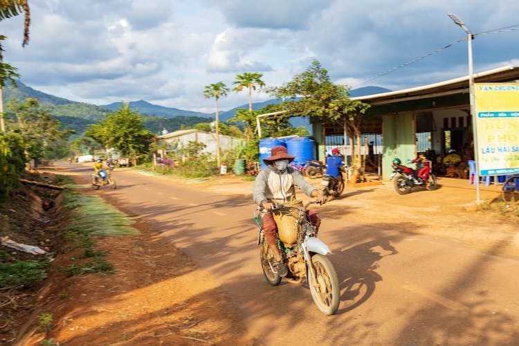 A Man With A Hat Riding A Motorcycle