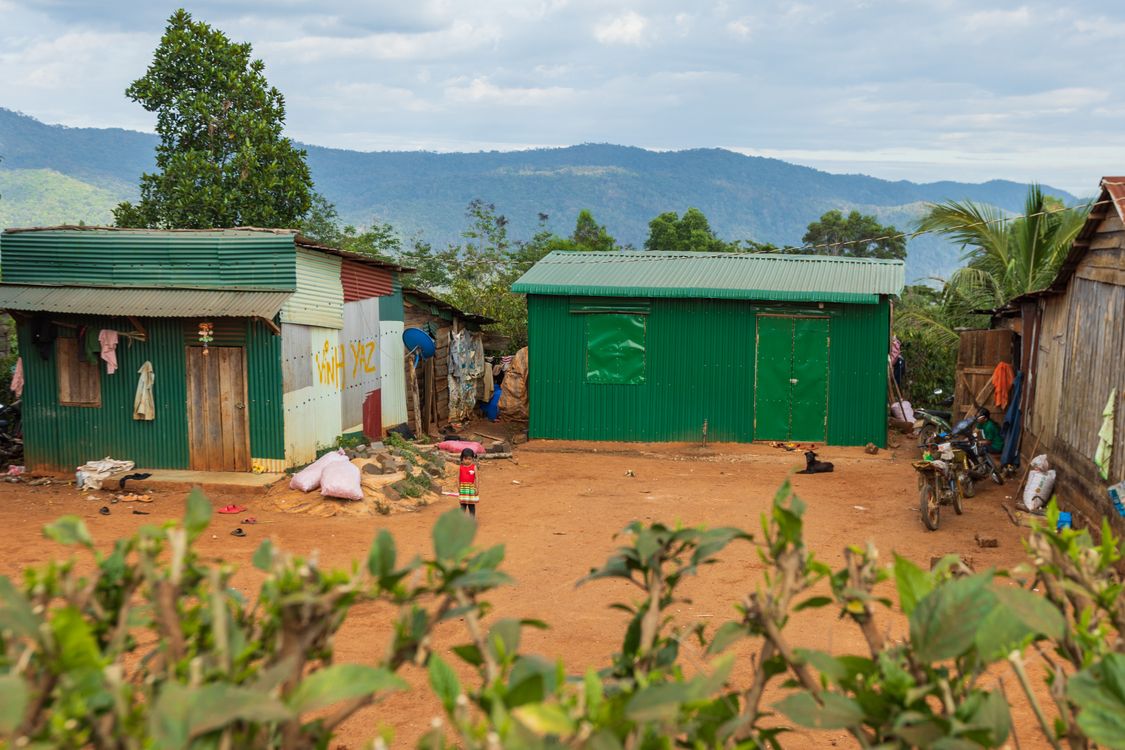 Free Colorful metal houses in a rural setting with mountain backdrop and a young child in vibrant clothing. Stock Photo