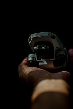 Close-up of a drone being held in a person's hand, set against a dark background, showcasing modern technology.