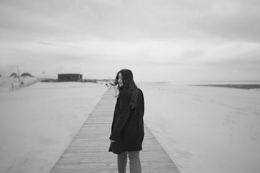 Black and white photo of a woman walking on a sandy beach in Portugal.