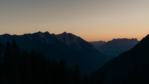 Free Serene mountain range silhouette at dusk with a warm glow in the sky. Stock Photo