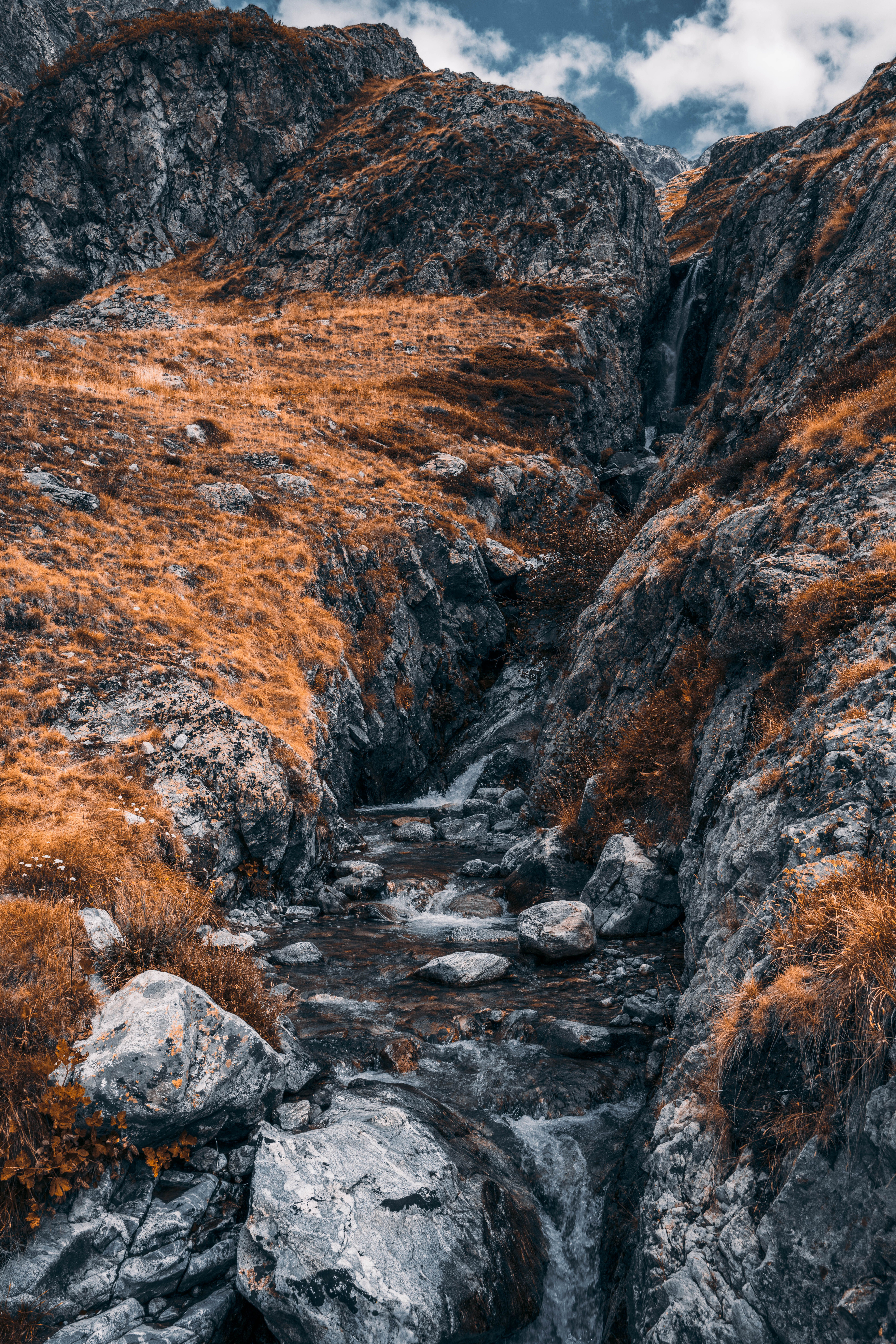Serene mountain stream flowing through rocky terrain in a vibrant autumn landscape.
