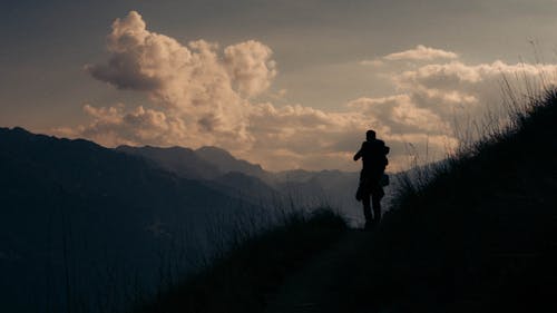 Silhouette of a Hiker Standing Across the White Clouds