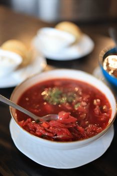 Close-up of a bowl of vibrant borscht soup with a spoon, garnished with herbs, perfect for food photography.