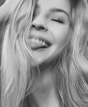 Expressive black and white headshot of a woman with long hair and closed eyes.