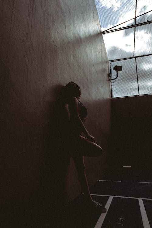 Woman Standing with Her Back against a Wall in a Dark Interior 