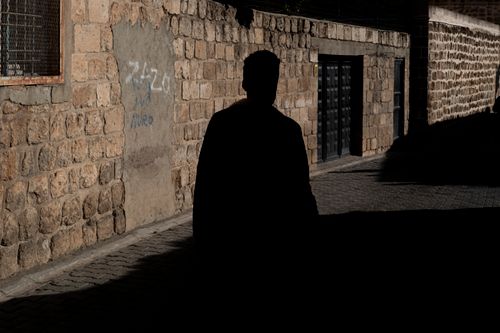 Free A silhouette of a pedestrian walking through the stone alleys of Midyat, Türkiye. Stock Photo