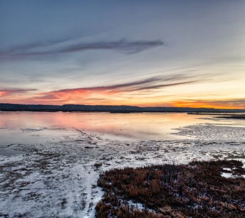 Free Scenic winter view of frozen Weaver Lake at sunset with vibrant skies reflecting on icy waters. Stock Photo