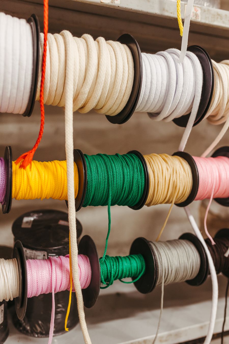 Spools of ribbon and cord on a workshop rack