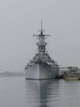 Photo by Jesús Martín A historic battleship moored at Pearl Harbor, captured on an overcast day, symbolizing naval history.